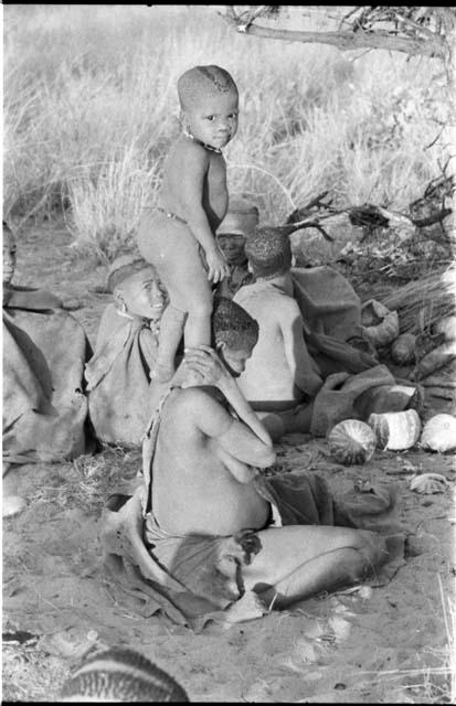 N!whakwe standing on his mother Tsekue's shoulders