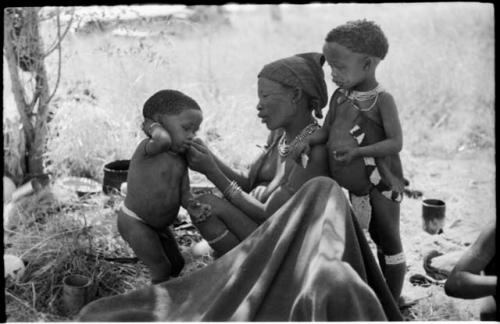 Debe standing beside !U, who is fixing his beads; and Norna leaning against her mother's shoulder