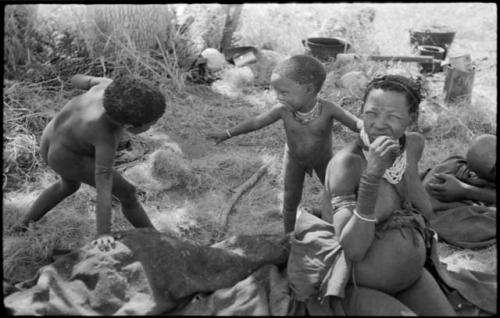 Di!ai sitting, with her son, Debe, standing behind her and smiling at another child