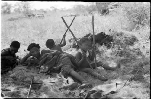 //Khuga nursing Bau, and /Naoka (Di!ai's co-wife) lying down, and Debe and /Gaishay sitting and holding sticks