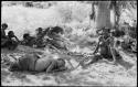 Group of people resting in the shade, including //Khuga, /Naoka, Debe and /Gaishay, with !U asleep and Elizabeth Marshall Thomas taking notes