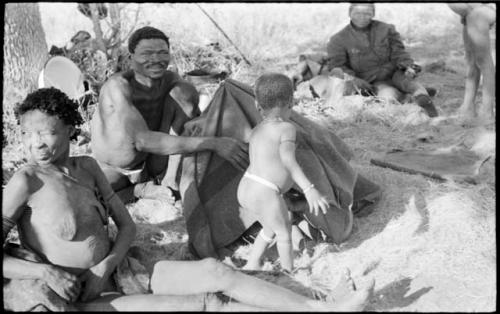 /Naoka and "Gao Medicine" sitting next to a group of children under a kaross