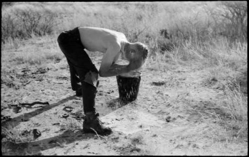 Man washing his face in a bucket