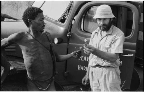 "Gao Medicine" standing near the expedition truck with Robert Story examining a plant