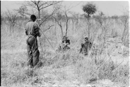 Two people in brush, being filmed by John Marshall