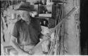 Thomas Hardbattle standing in his store-room and holding a gun