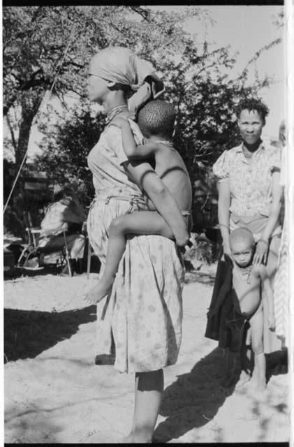 Woman wearing a dress and holding her child on her back