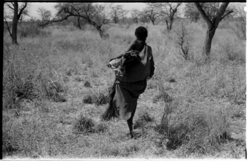 Woman carrying meat in a kaross seen from behind