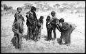 Ju/'hoan youth crowded around a girl wearing a laced boot