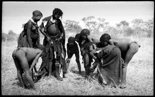 Ju/'hoan youth crowded around a girl wearing a laced boot