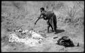 Di!ai preparing to cook a wildebeest head by stirring coals with a stick