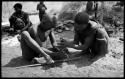 Dam and ≠Gao creating a fire with firesticks; unidentified people in the background