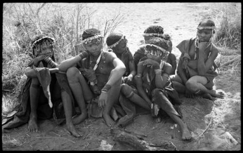 Six girls sitting with wreaths of blossoms around their heads