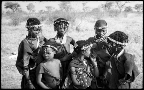 Six girls with wreaths of blossoms on their heads, all standing