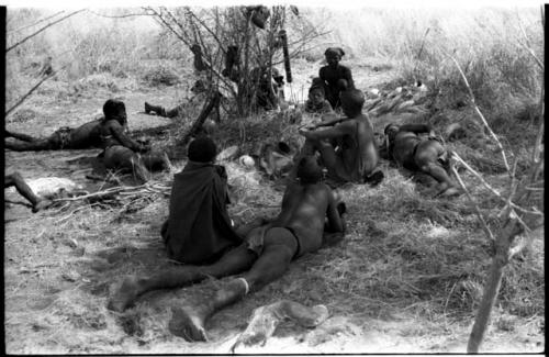 Group of men and boys lying and sitting in the shade