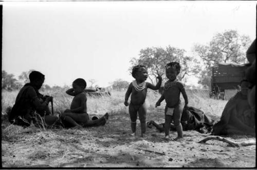 Khuan//a with /Qui sitting on her legs and ≠Toma (Khuan//a's son) standing with an unidentified girl