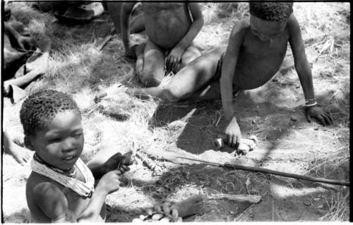 "Little ≠Gao" pushing a handmade toy automobile made from veldkos and other unidentified children