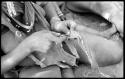 Woman's hands sewing beads onto a leather strip, close-up