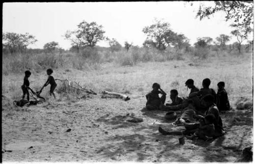 /Gaishay and Bau carrying the cooked wildebeest head away from a group of women and children