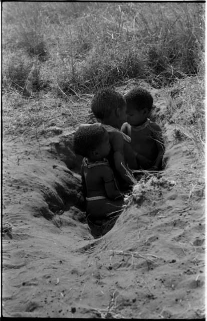 /Gaishay, Bau, and Debe playing in a hole in the ground