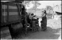 Children playing around the expedition truck while Di!ai stands beside them; the expedition camp is in the background