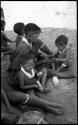 Di!ai giving food to her sons, /Gaishay and Debe