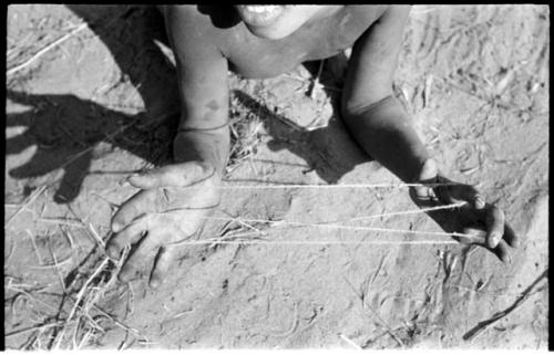 Child's hands holding a "cat's cradle" in an early stage