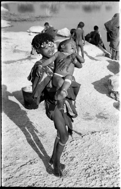 N!ai holding Debe, her half-brother; unidentified people in the background