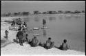 Group of women and children beside the water; Debe is running toward N!ai