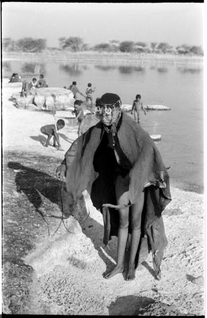 Woman bathing at Nama Pan, standing with her kaross over her shoulder; unidentified children in the background