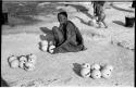 Khuan//a (Gau's wife) sitting with ostrich egg shells