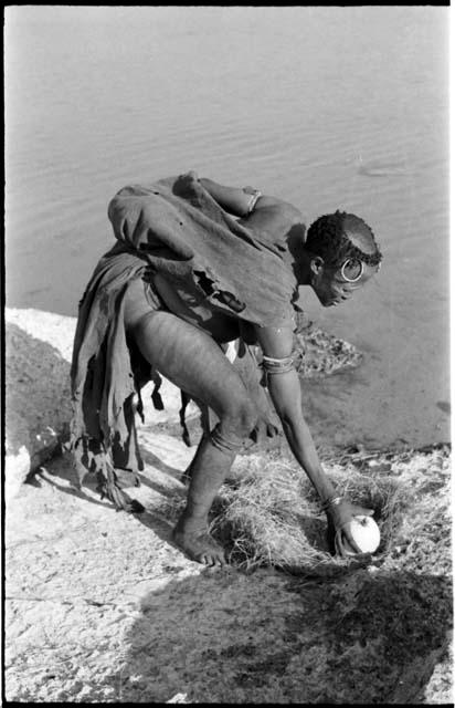 Khuan//a (Gau's wife) picking up an ostrich eggshell