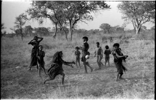 Girls playing N!owa t/ama (melon tossing game) / tamah n!o’an (ball game); other children present in the background