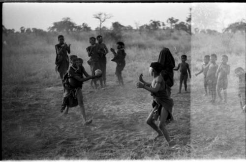 Girls playing N!owa t/ama (melon tossing game) / tamah n!o’an (ball game); an unidentified, visiting girl catches the melon while other children watch in the background