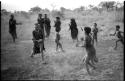 Girls playing N!owa t/ama (melon tossing game) / tamah n!o’an (ball game); an unidentified visiting girl catches the melon; other children in the background