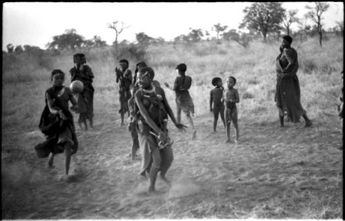 Girls playing N!owa t/ama (melon tossing game) / tamah n!o’an (ball game); !Ungka's cousin catches the ball from an unidentified, visiting girl while other children watch in the background