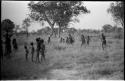 Girls playing N!owa t/ama (melon tossing game) / tamah n!o’an (ball game); other children are watching and running, distant view