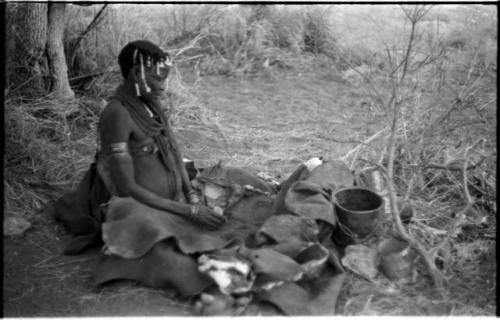 Woman pounding bone and red powder in her kaross with a stone