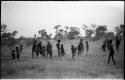 Group of youths; a boy is holding aloft the melon with which girls were playing N!owa t/ama (melon tossing game) / tamah n!o’an (ball game)