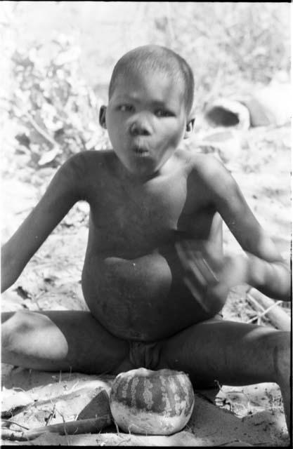 Boy eating tsama melon, seated