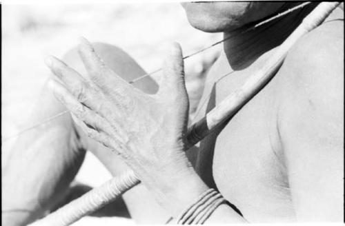 Close-up of Oukwane's hand and chin, demonstrating how to play a musical bow