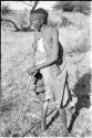 /Twikwe standing leaning on digging stick, full figure