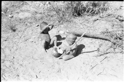 N!whakwe and a "visiting baby" playing with a tsama melon and a digging stick