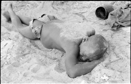 Oukwane lying on his stomach, with sand sprinkled on his back