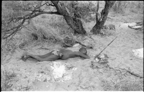 Oukwane lying on his stomach, with sand sprinkled on his back