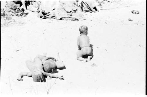 Three little boys playing, rolling in the sand