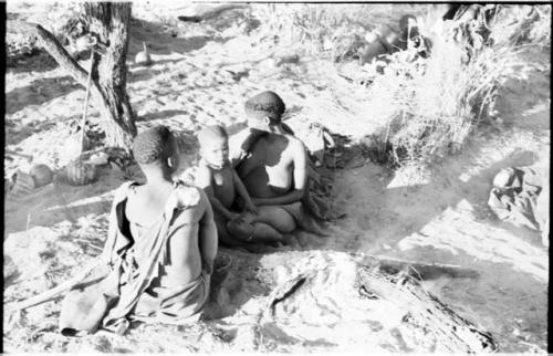 Visiting women and a child sitting by their fire