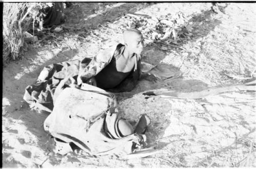 Two men lying on the ground, wrapped in karosses