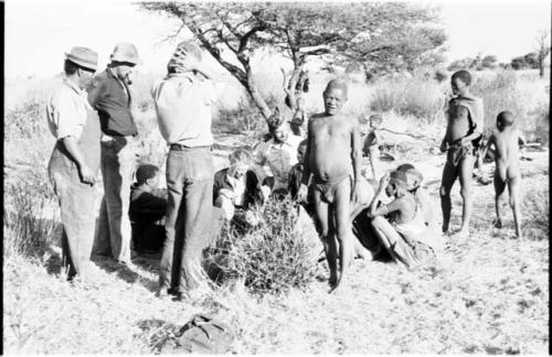 Group of people, including Oukwane and !Gai, being interviewed by Lorna Marshall and Elizabeth Marshall, with Casper Kruger, Kernel Ledimo, Wilhelm Camm, John Marshall, and Daniel Blitz watching