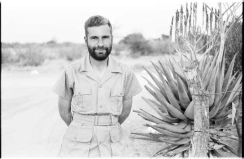 Daniel Blitz with a beard, standing by aloe plant